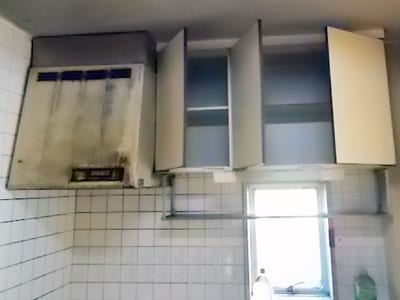 リフォーム前のシステムキッチン、上部の換気扇と棚の写真。汚れが激しいです。