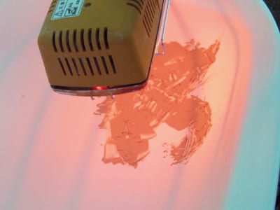 洗面ボウルのヒビ割れ補修の写真、乗せたパテに特殊な光を当てているところの写真