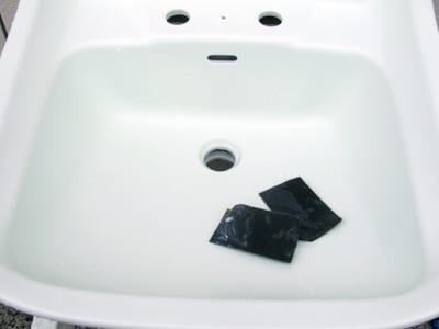 洗面ボウルのヒビ割れ補修の写真、ベースコートを乾燥させたら、ペーパーでざらつきをきれいに取り除いているところの写真1